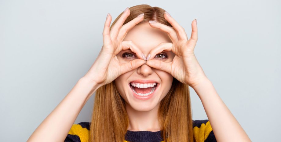 woman makes circle with her hands and places them over her eyes