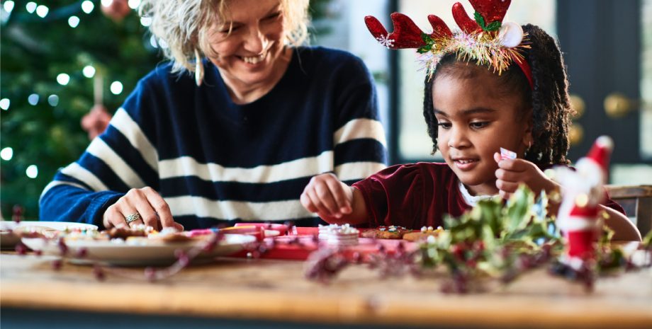 Older woman building holiday crafts with a younger child.