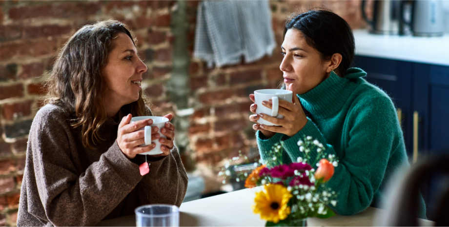 Two women having a discussion with coffee cups in their hands.